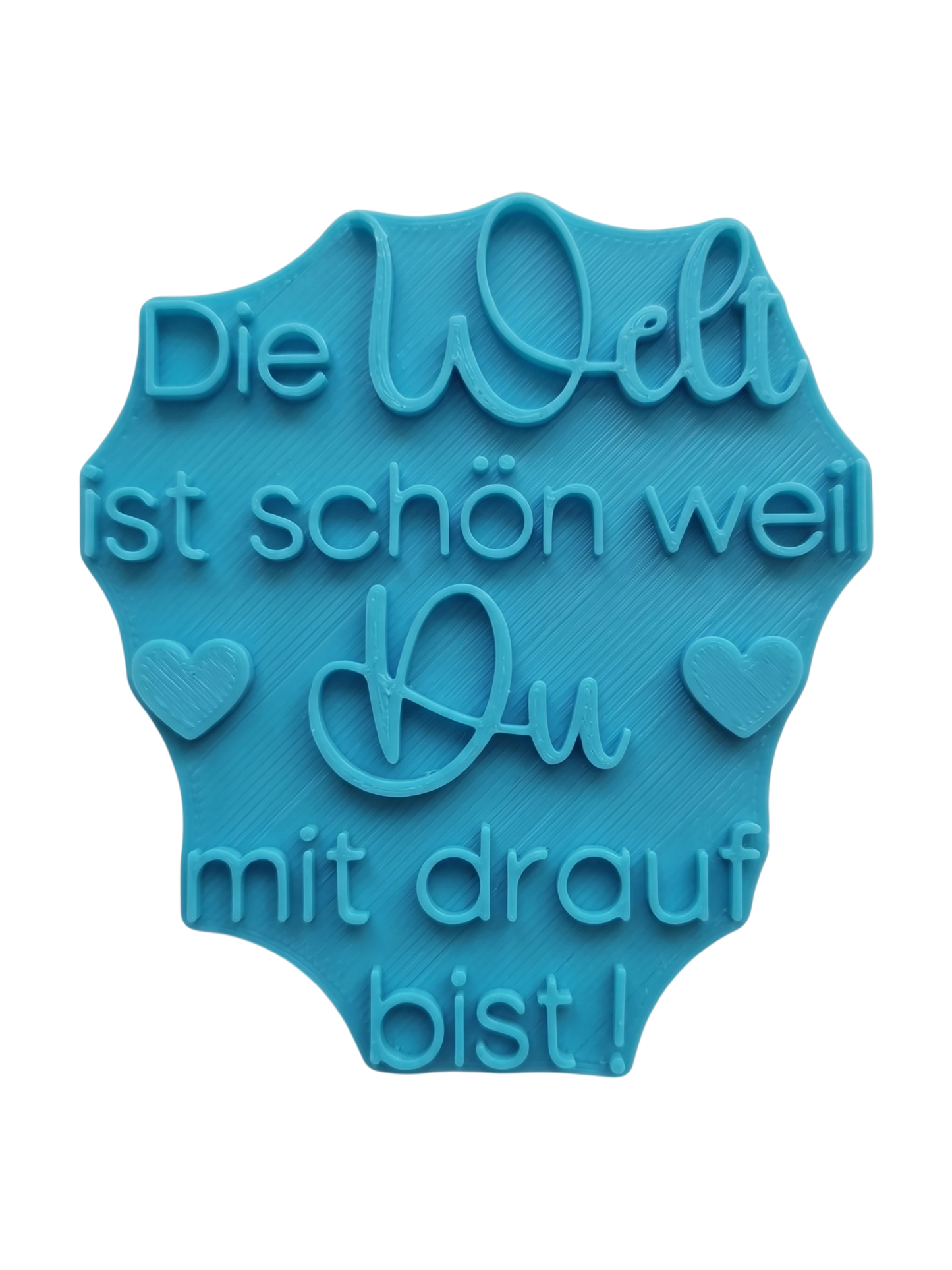 Der blaugrüne MinseArt Textstempel mit dem Spruch 'Die Welt ist schön weil Du mit drauf bist!'. Hochwertiges Töpferwerkzeug für Ton-Projekte. Stabiler Stempel für tiefe, saubere Prägungen in Keramik, ideal für dein nächstes DIY-Projekt.