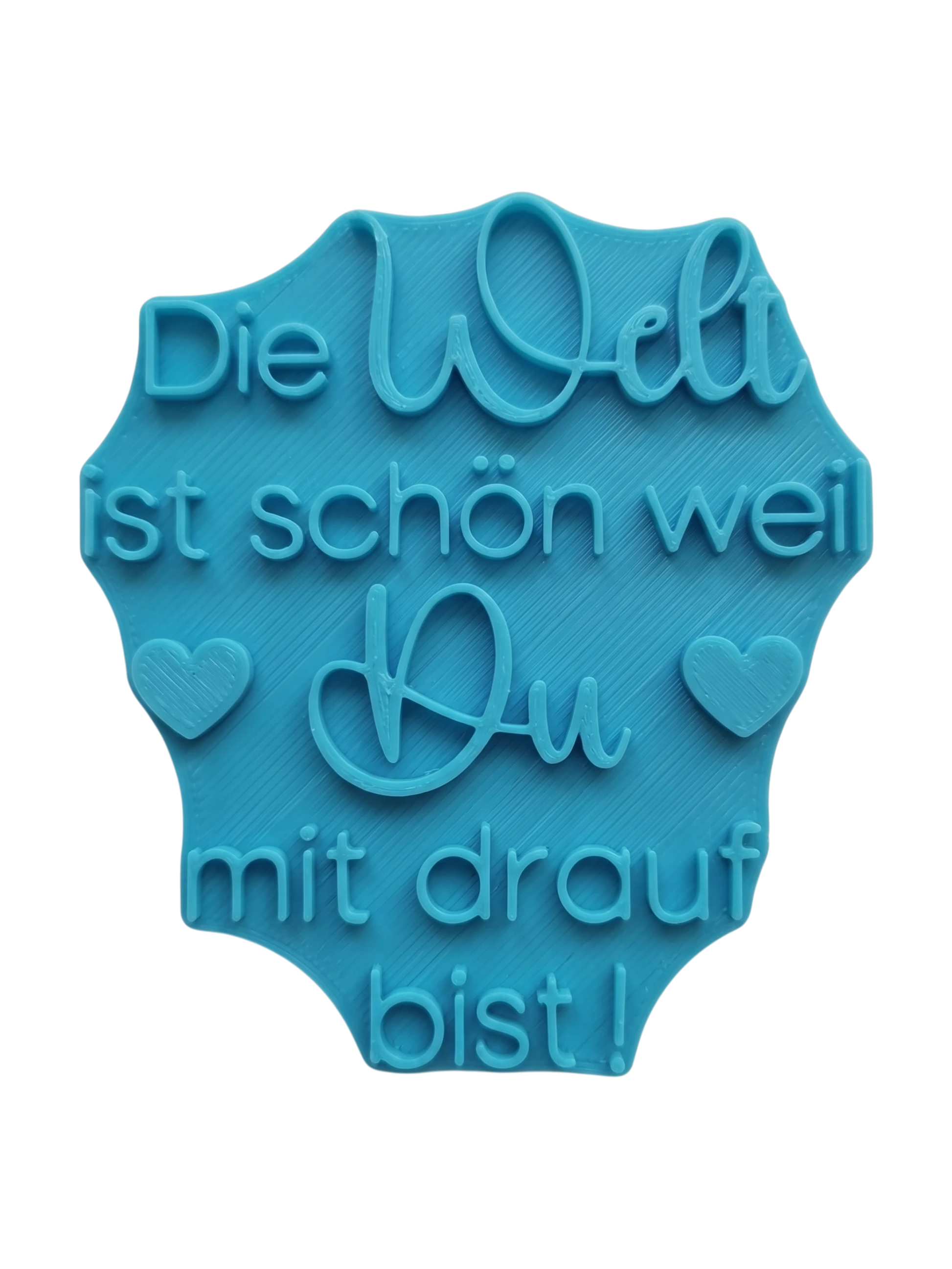 Der blaugrüne MinseArt Textstempel mit dem Spruch 'Die Welt ist schön weil Du mit drauf bist!'. Hochwertiges Töpferwerkzeug für Ton-Projekte. Stabiler Stempel für tiefe, saubere Prägungen in Keramik, ideal für dein nächstes DIY-Projekt.