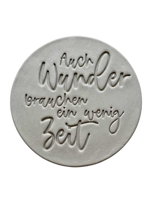 Detailreicher Abdruck im Ton mit dem Spruch 'Auch Wunder brauchen ein wenig Zeit'. Erstellt mit einem MinseArt Keramikstempel. Saubere Konturen und feine Schriftzüge für deine nächste Töpfer-Idee im Bereich Baby und Kinderzimmer.
