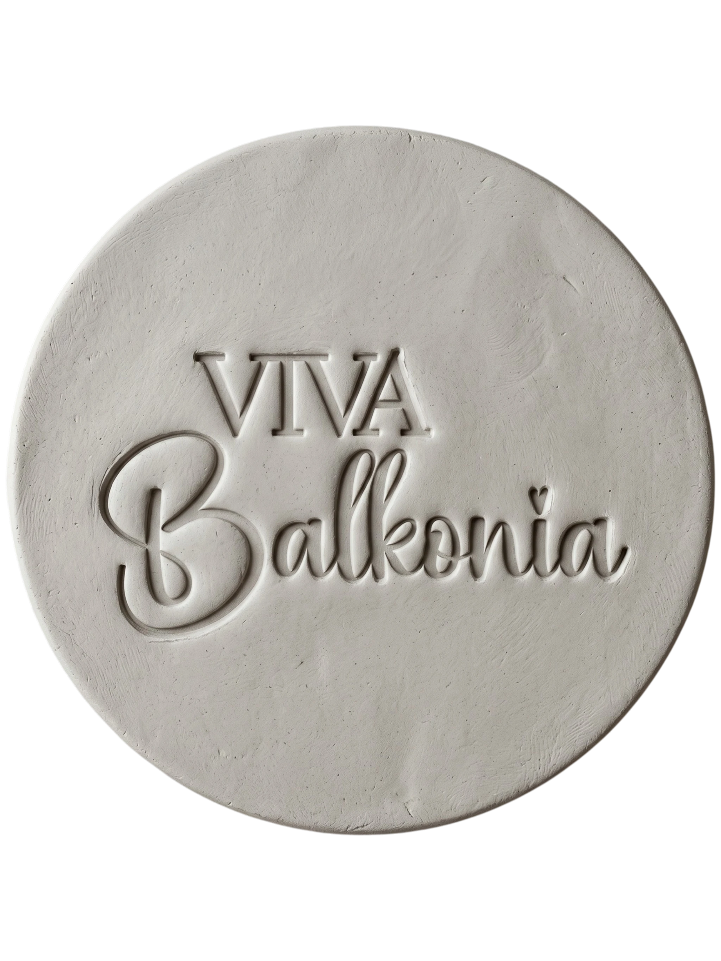 Präziser Stempelabdruck des Schriftzugs 'VIVA Balkonia' in hellem Ton. Das saubere, tiefe Relief auf der runden Tonplatte zeigt die harmonische Kombination aus klarer Druckschrift und verspielter Schreibschrift mit einem kleinen Herz-Detail über dem i. Ein perfektes Töpfer-Ergebnis mit einem MinseArt Keramikstempel.