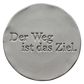 Präziser Stempelabdruck 'Der Weg ist das Ziel' in hellem Ton. Sauberes, tiefes Relief auf einer runden Tonplatte, erstellt mit einem MinseArt Textstempel