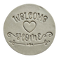 Präziser Stempelabdruck 'Welcome Home' mit Herz-Motiv in hellem Ton. Das saubere Relief kombiniert verspielte Druckschrift mit eleganter Schreibschrift auf einer runden Tonplatte.