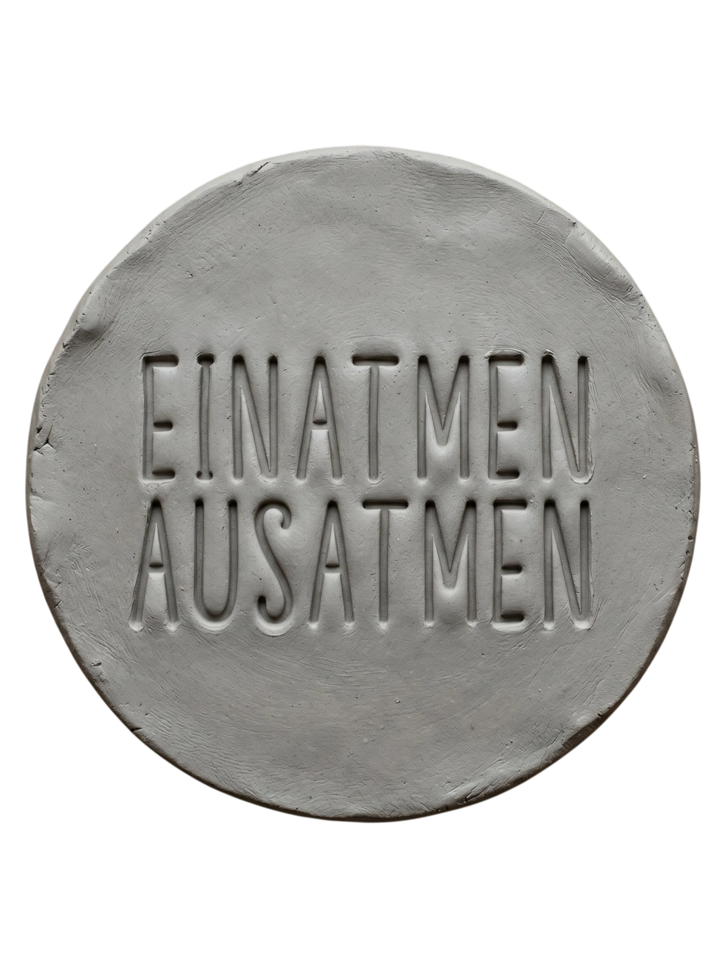 Sauberer Stempelabdruck 'Einatmen Ausatmen' in hellem Ton. Das tiefe Relief der klaren Typografie sorgt für ein minimalistisches Design auf der runden Tonplatte.