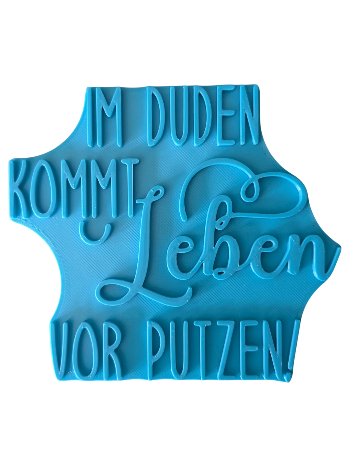 Türkisfarbener Keramikstempel für Ton mit dem lustigen Spruch 'Im Duden kommt Leben vor Putzen'. Hochwertiges Töpferzubehör für präzise Textprägungen.