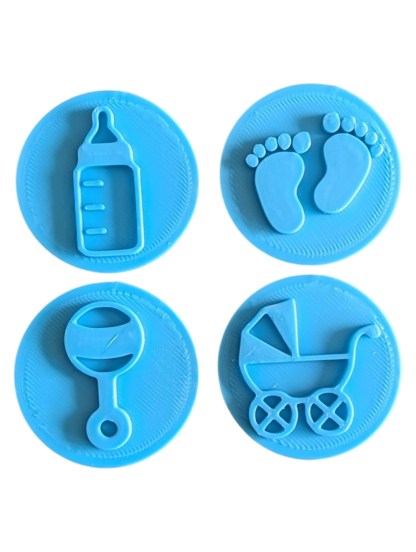Draufsicht auf das vierteilige Keramikstempel-Set für Ton mit süßen Baby-Motiven. Die runden Prägestempel zeigen detailreich eine Flasche, Füße, eine Rassel und einen Kinderwagen.