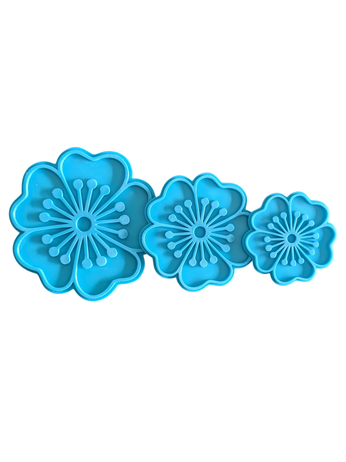 Die drei blauen Blumen-Tonstempel des 3er-Sets übersichtlich nebeneinander aufgereiht.