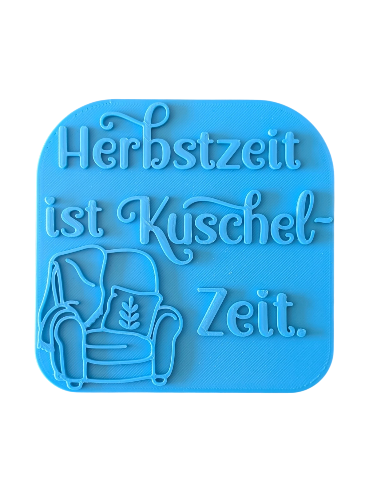 Direkte Draufsicht auf den freigestellten blauen Tonstempel Herbstzeit ist Kuschelzeit mit Sessel-Illustration.