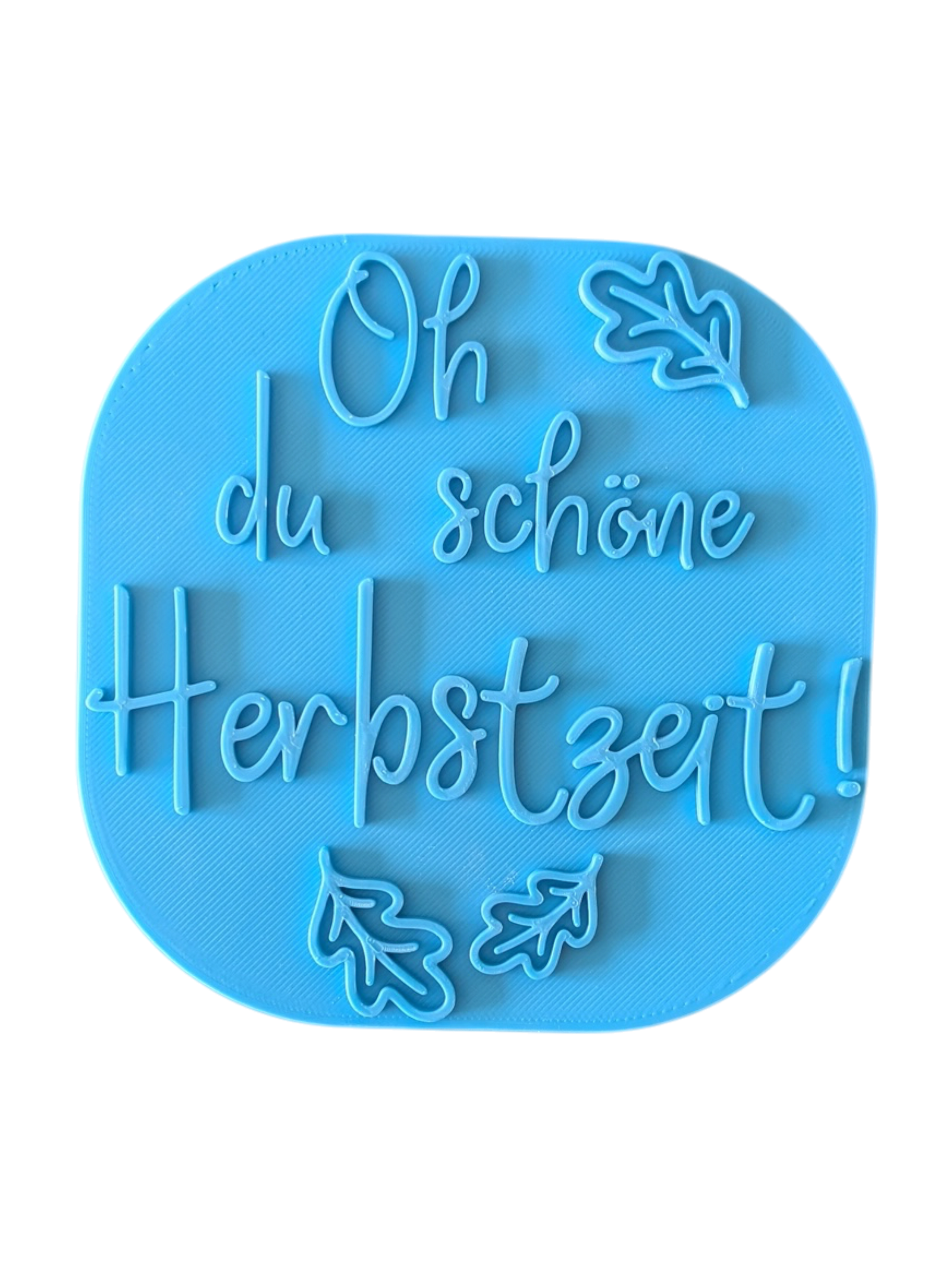 Direkte Draufsicht auf den freigestellten blauen Tonstempel Oh du schöne Herbstzeit mit Herbstblättern.