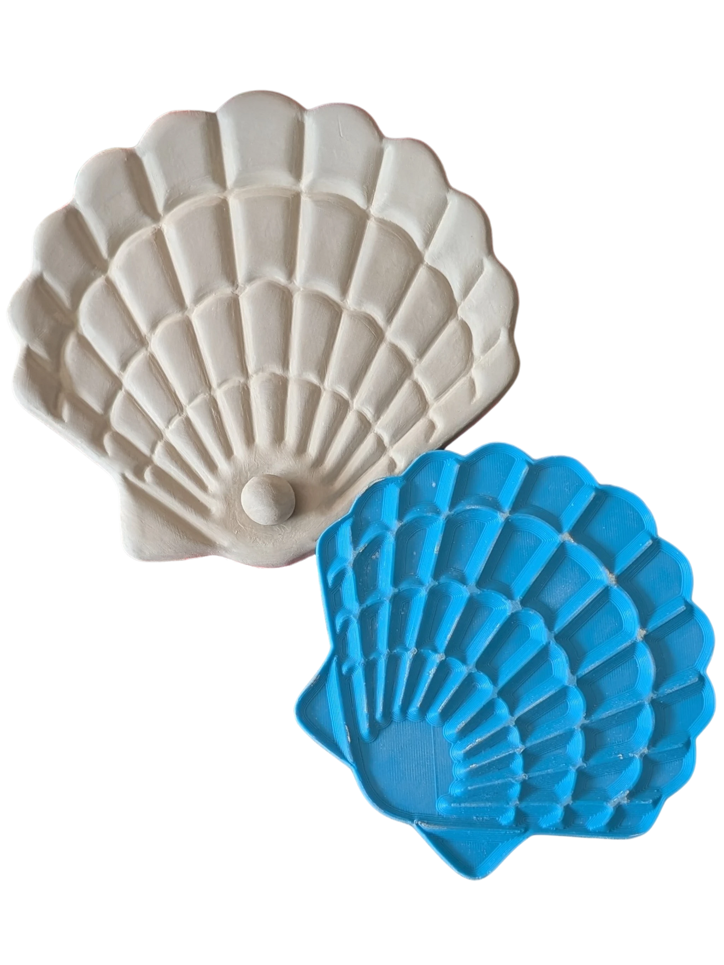 Draufsicht auf den blauen Muschel-Stempel von MinseArt neben einem perfekten hellen Tonabdruck mit kleiner Perle, auf schwarzem Hintergrund.