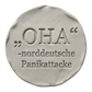 Präziser Stempelabdruck des witzigen Spruchs 'OHA - norddeutsche Panikattacke' in hellem Ton. Sauberes, tiefes Relief mit klarer Typografie auf einer runden Tonplatte.