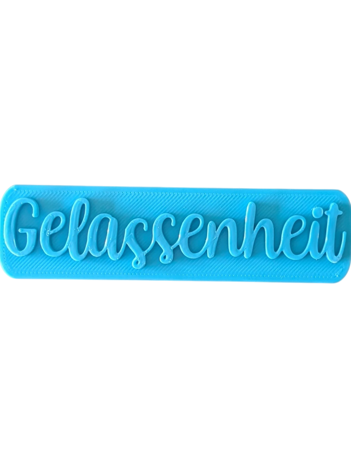 Direkte Draufsicht auf den blauen Tonstempel mit dem Schriftzug Gelassenheit und feinen Konturen.