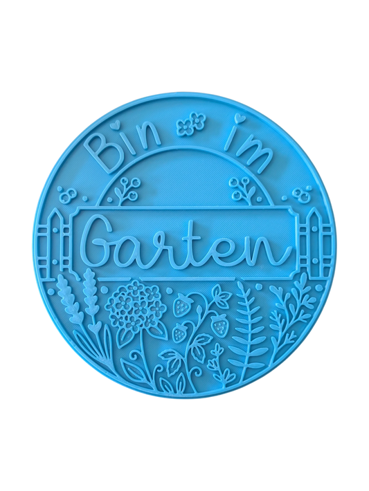 Draufsicht auf den Prägestempel für Ton mit dem Spruch 'Bin im Garten'. Das sommerliche Motiv kombiniert den Text mit einem Zaun, Erdbeeren, Lavendel und filigranen Blüten.