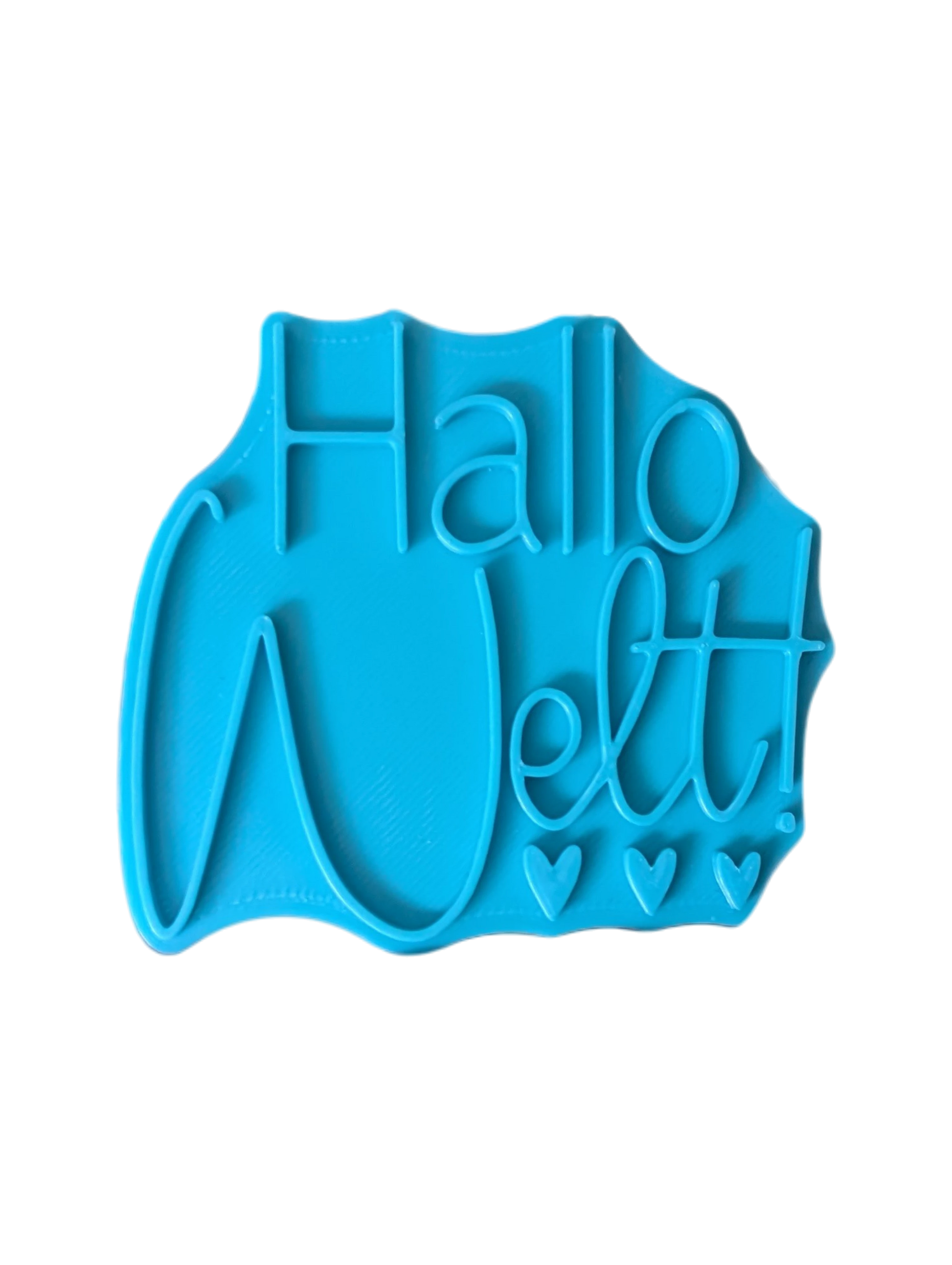 Draufsicht auf den Prägestempel für Ton mit dem Schriftzug 'Hallo Welt!'. Ein detailreicher Textstempel mit drei kleinen Herzen für handgemachte Baby-Keramik zur Geburt.