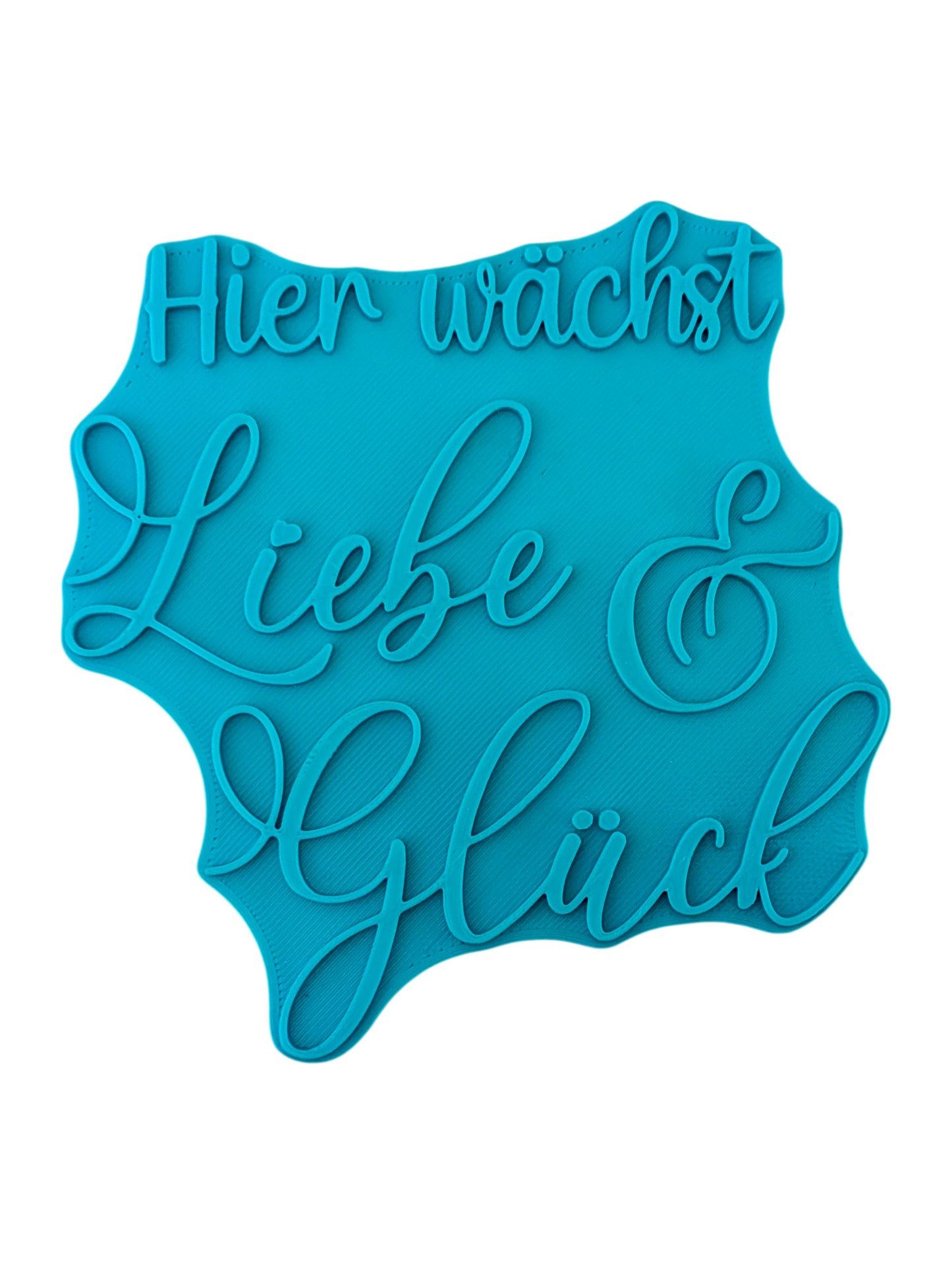 Draufsicht auf den Prägestempel für Ton mit dem Schriftzug 'Hier wächst Liebe & Glück'. Ein detailreicher und eleganter Textstempel für handgemachte Keramik-Deko.