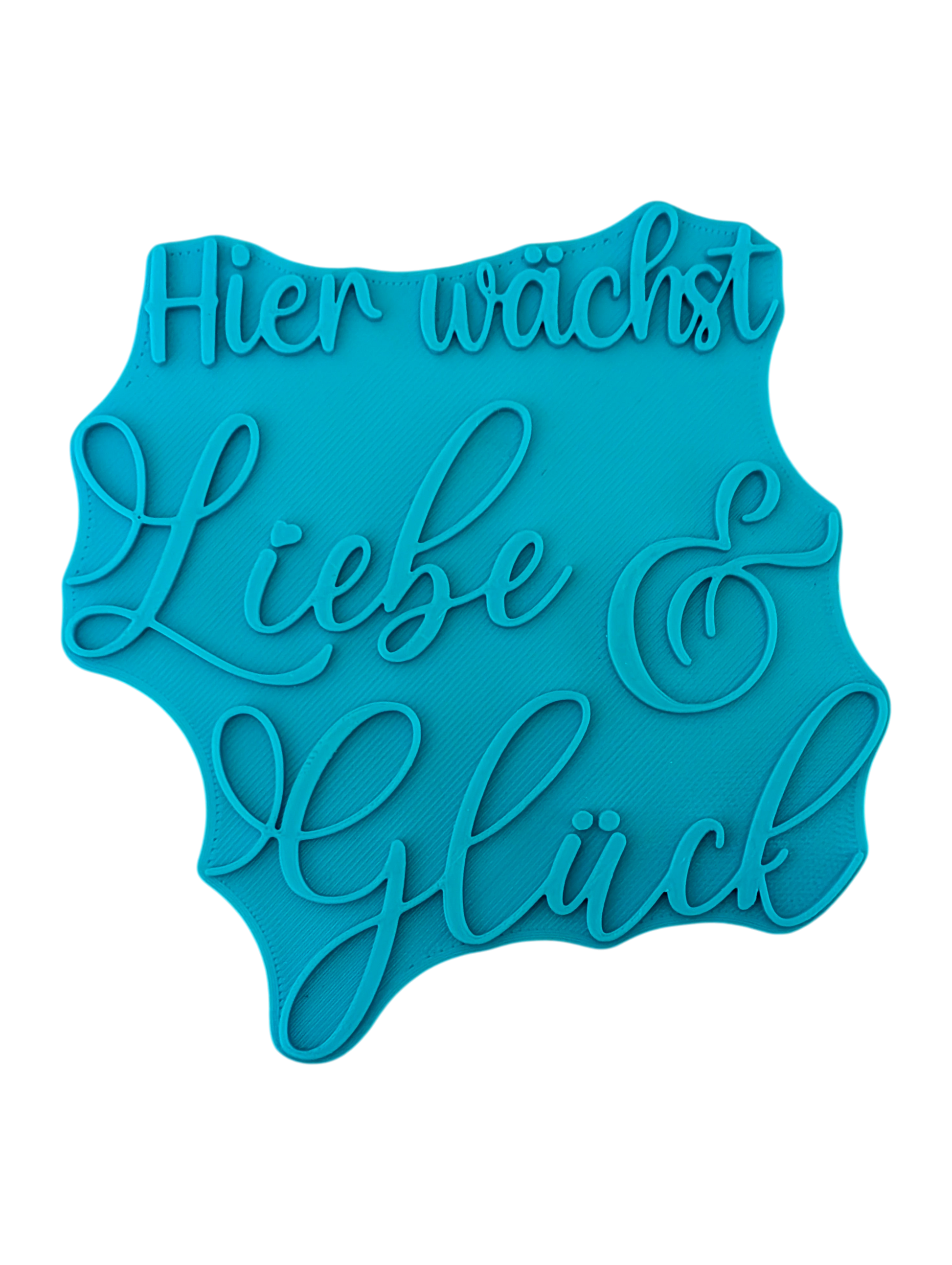Draufsicht auf den Prägestempel für Ton mit dem Schriftzug 'Hier wächst Liebe & Glück'. Ein detailreicher und eleganter Textstempel für handgemachte Keramik-Deko.