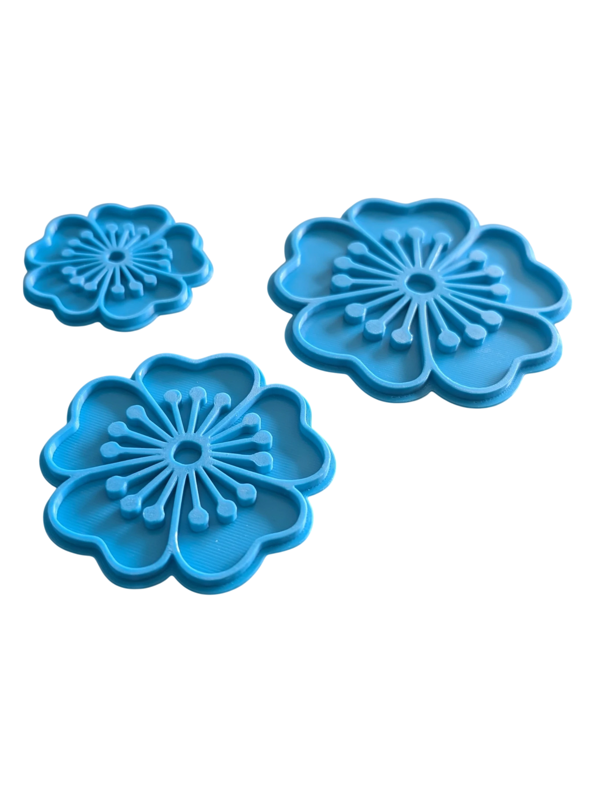 Perspektivische Detailansicht der drei blauen Blumen-Stempel für Töpferprojekte mit präzisen Konturen.