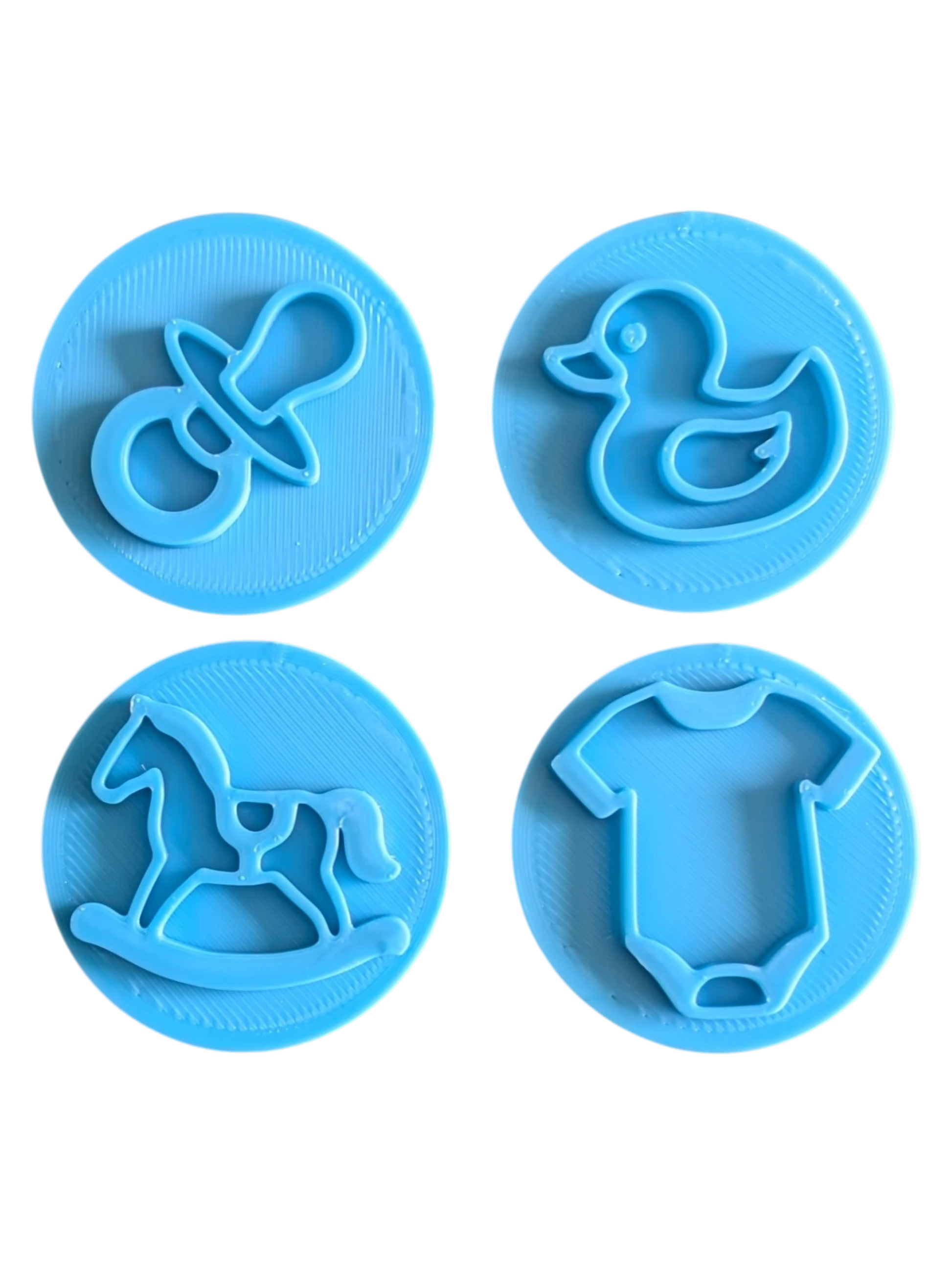 Schrägansicht der türkisfarbenen Tonstempel mit Baby-Motiven. Das handgefertigte Töpferwerkzeug besticht durch tiefe, präzise Konturen für perfekte Abdrücke in der Modelliermasse.