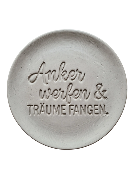 Sauberer Stempelabdruck des Textstempels Anker werfen & Träume fangen in hellem, unglasiertem Ton. Die Kombination aus Druck- und Schreibschrift sowie den Vögeln kommt als tiefes Relief perfekt zur Geltung.