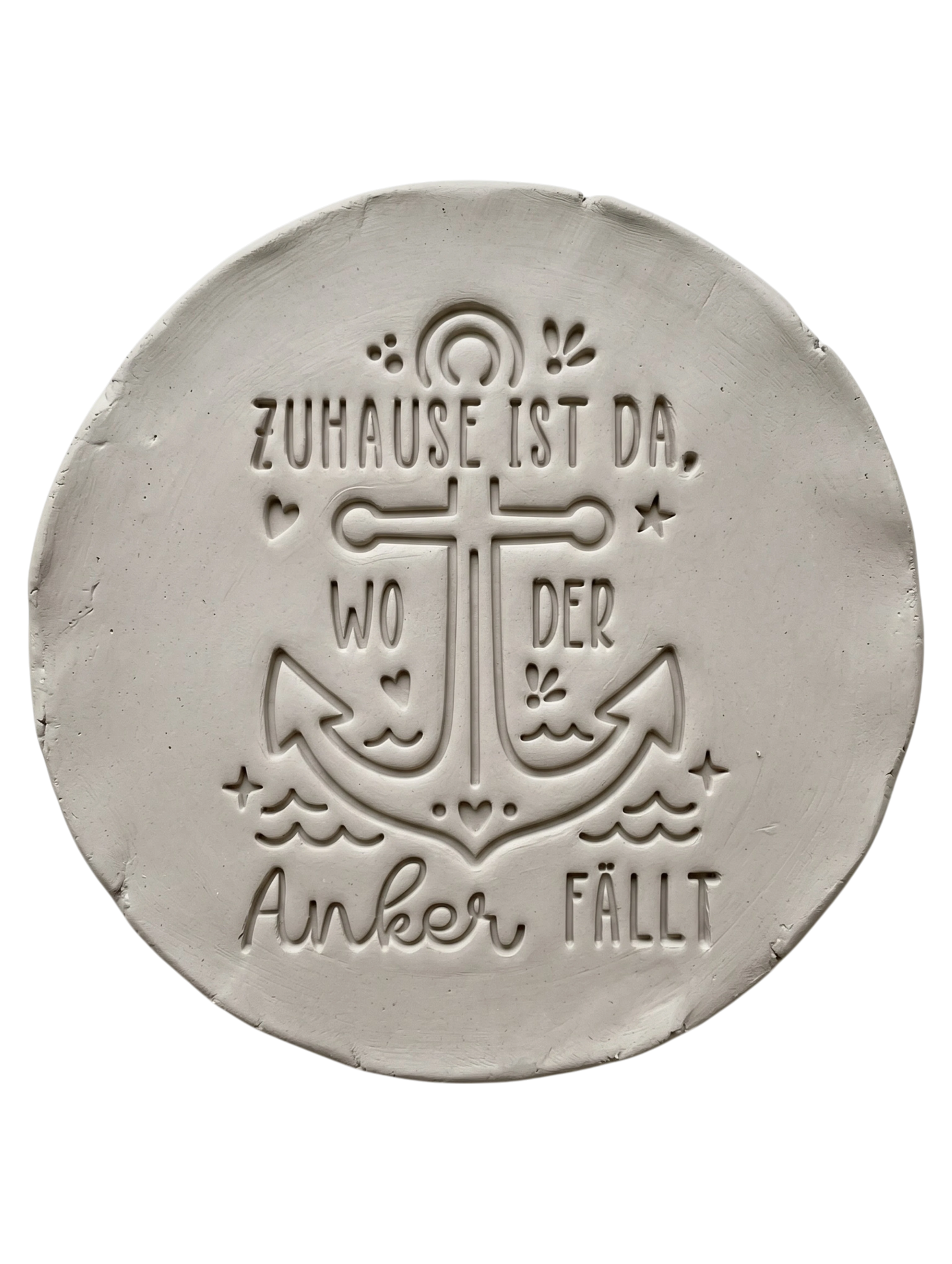Präziser Stempelabdruck des maritimen Textstempels 'Zuhause ist da, wo der Anker fällt' in hellem Ton. Das tiefe Relief zeigt den Anker und die Schrift perfekt auf einer runden Tonplatte.