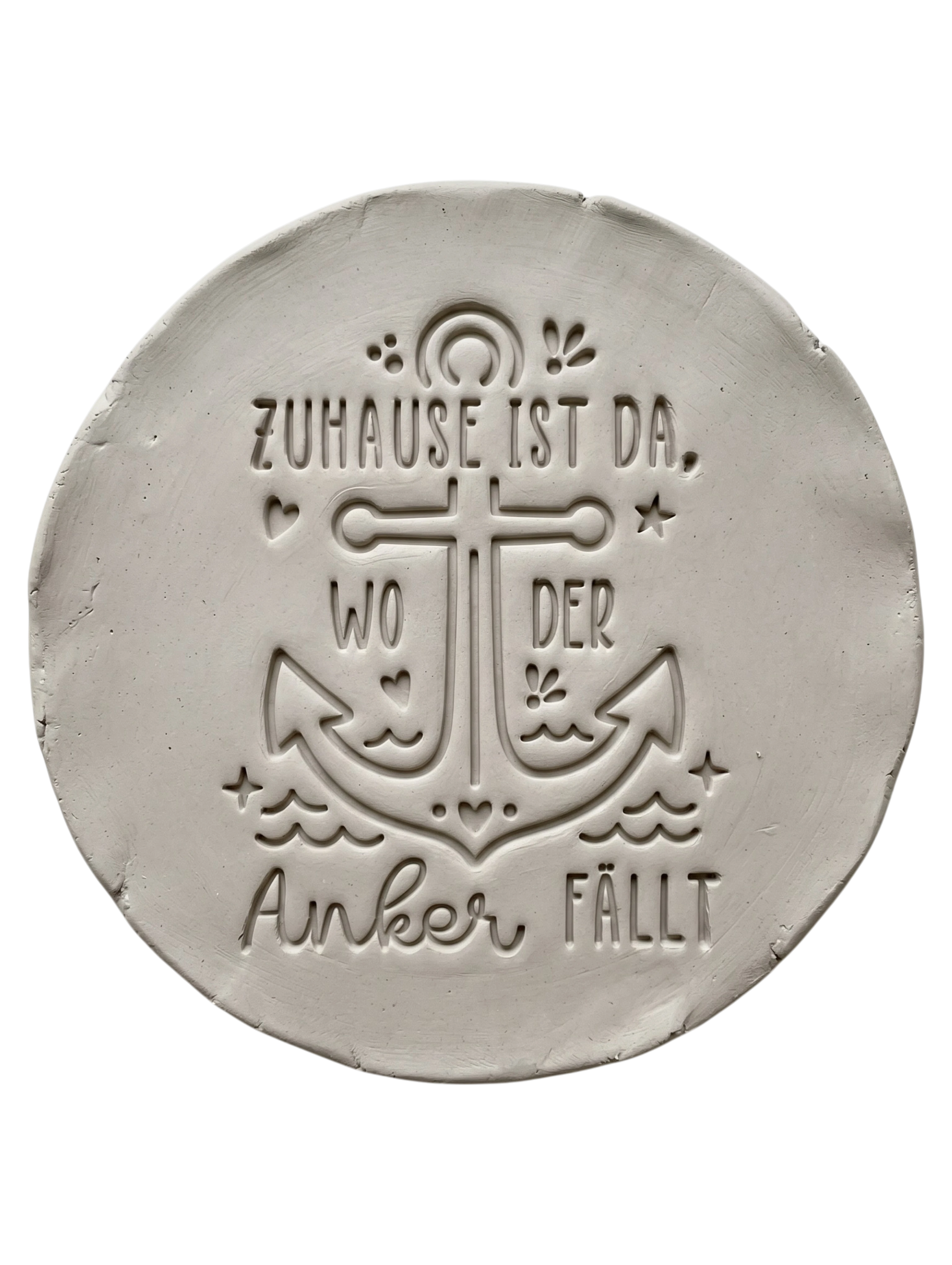 Präziser Stempelabdruck des maritimen Textstempels 'Zuhause ist da, wo der Anker fällt' in hellem Ton. Das tiefe Relief zeigt den Anker und die Schrift perfekt auf einer runden Tonplatte.