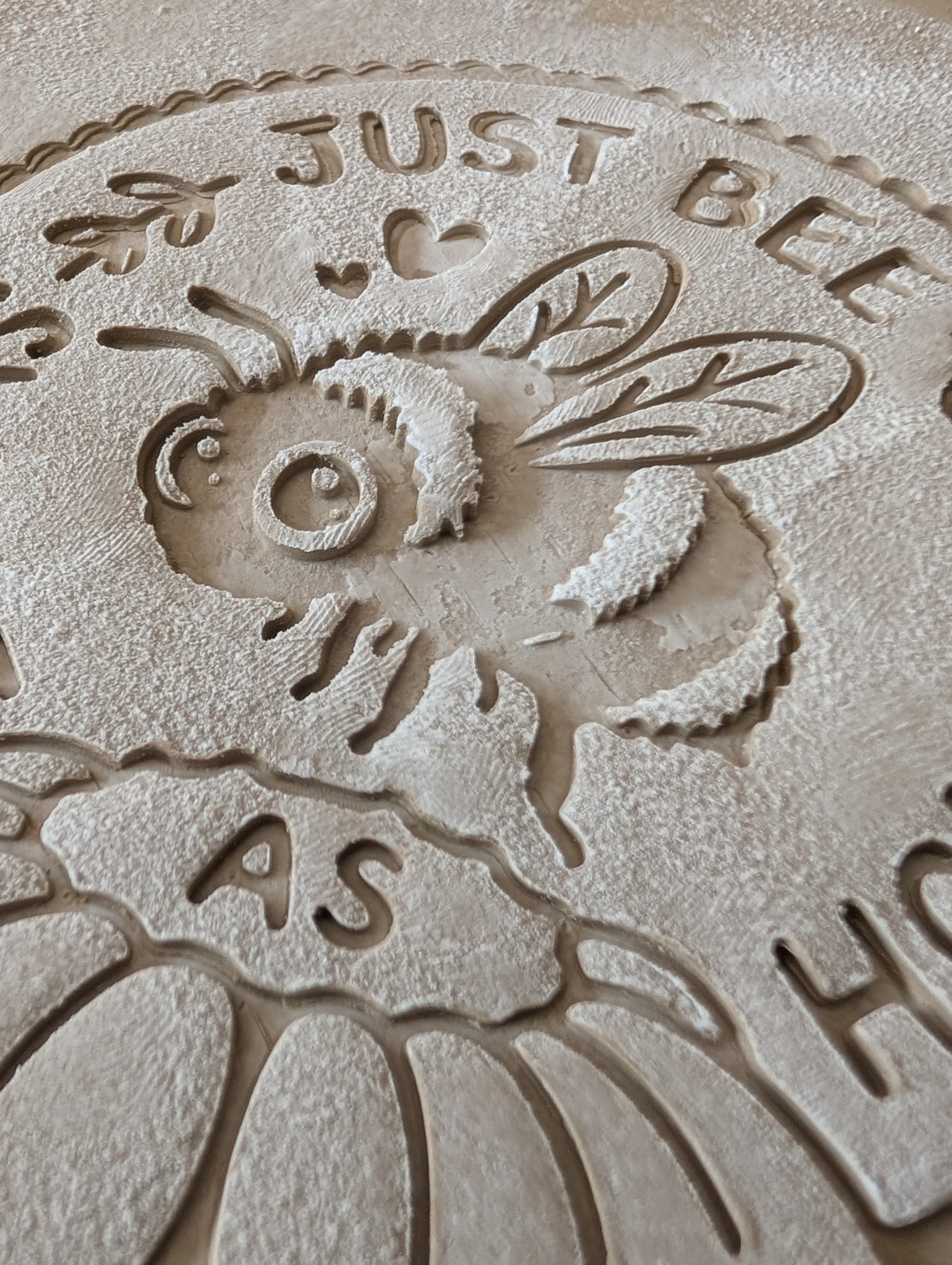 Sauberer Stempelabdruck des Bienen-Motivs in unglasiertem Ton, leicht bemehlt. Die feinen Details der Biene, der Blüte und der Schrift kommen auf der Tonplatte wunderschön zur Geltung.
