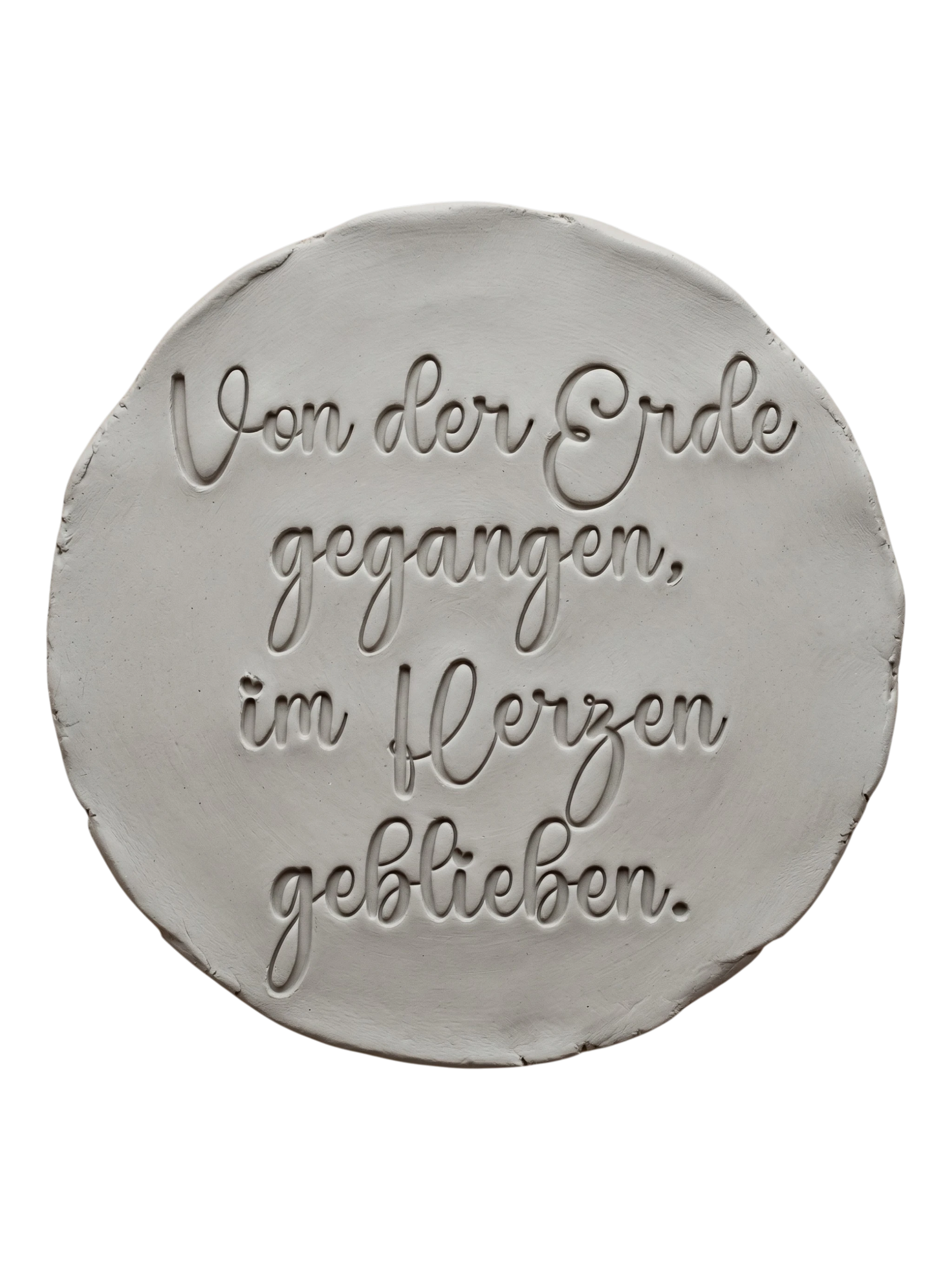 Präziser Stempelabdruck des Textstempels 'Von der Erde gegangen, im Herzen geblieben' in hellem Ton. Das detailreiche Relief zeigt die wunderschöne Schrift perfekt auf einer unglasierten, runden Tonplatte.