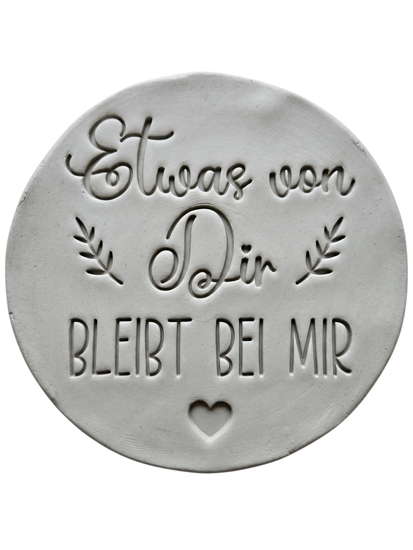 Präziser Stempelabdruck des Textstempels 'Etwas von dir bleibt bei mir' in hellem Ton. Das detailreiche Relief zeigt klare Schrift und florale Elemente perfekt auf einer unglasierten, runden Tonplatte.