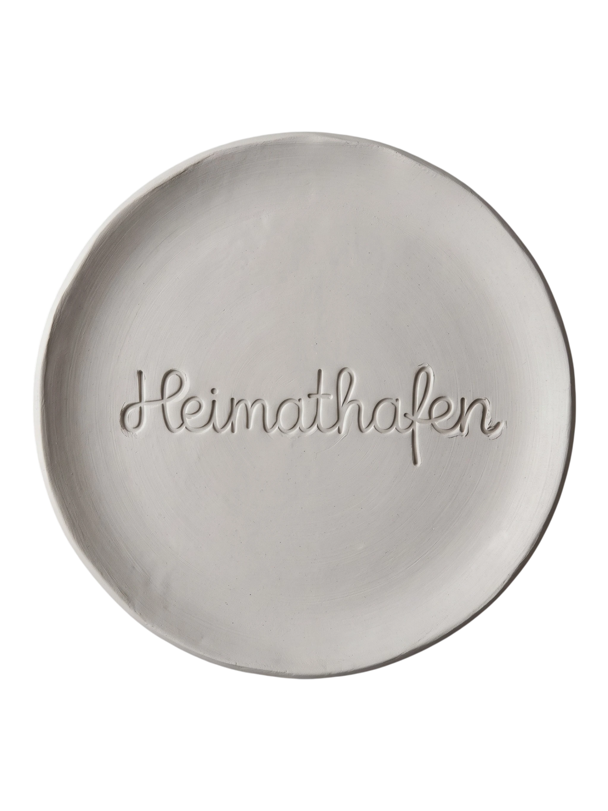 Sauberer Stempelabdruck des Textstempels 'Heimathafen' in hellem, unglasiertem Ton. Die fließende, zusammenhängende Schreibschrift kommt als tiefes Relief auf der runden Tonplatte perfekt zur Geltung.