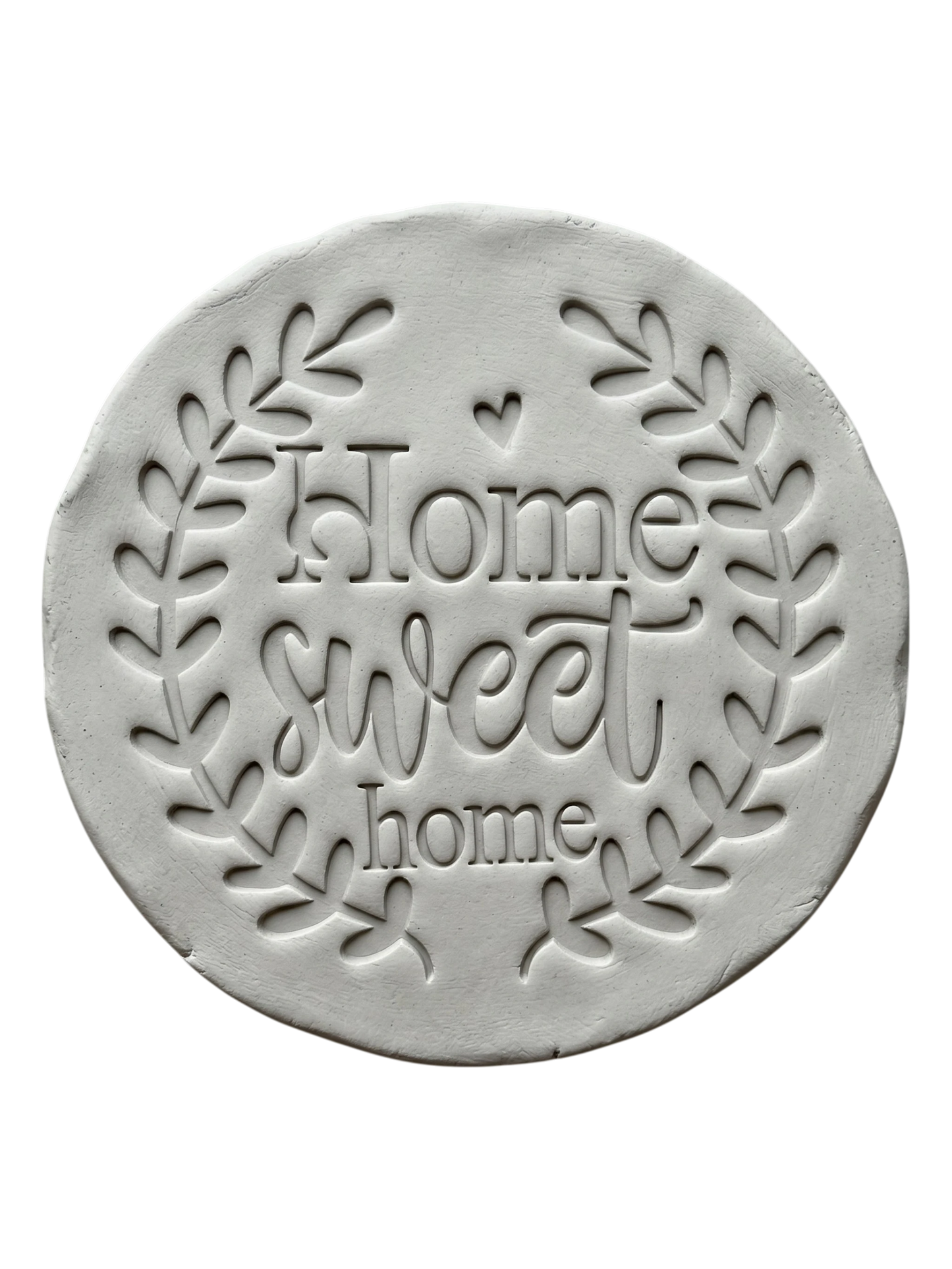 Sauberer Stempelabdruck des Prägestempels 'Home sweet home' in hellem Ton. Das detailreiche Relief zeigt den schönen Blätterkranz und den Schriftzug perfekt auf einer unglasierten, runden Tonplatte.