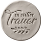 Sauberer Stempelabdruck des Textstempels 'in stiller Trauer' in hellem Ton. Das tiefe Relief zeigt die klare Schrift und die floralen Details perfekt auf einer unglasierten, runden Tonplatte.