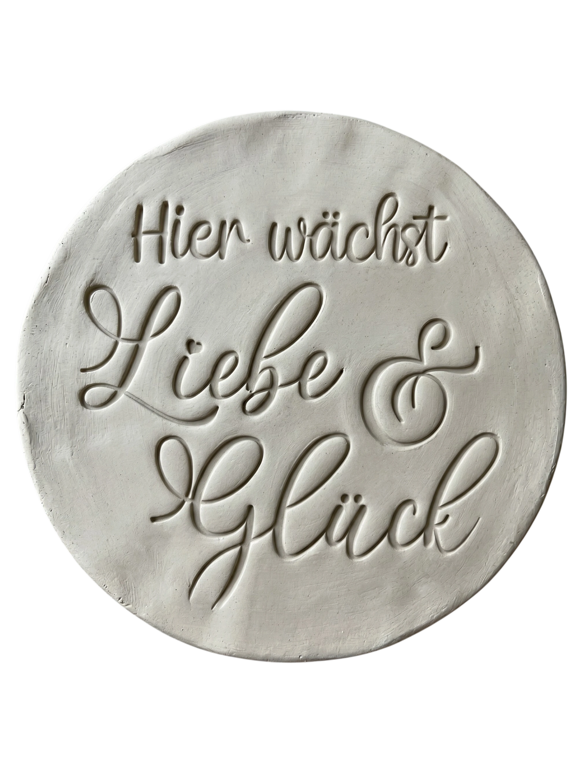 Sauberer Stempelabdruck des Textstempels 'Hier wächst Liebe & Glück' in hellem, unglasiertem Ton. Die elegante Schrift kommt auf der runden Tonplatte wunderschön zur Geltung.
