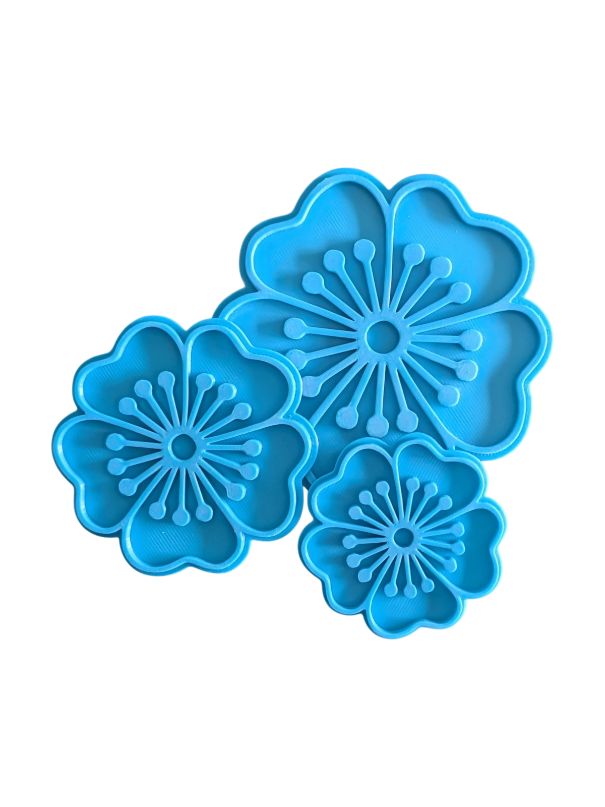 Direkte Draufsicht auf das freigestellte blaue 3er-Set Tonstempel mit Blumen-Umrissen für Keramik.