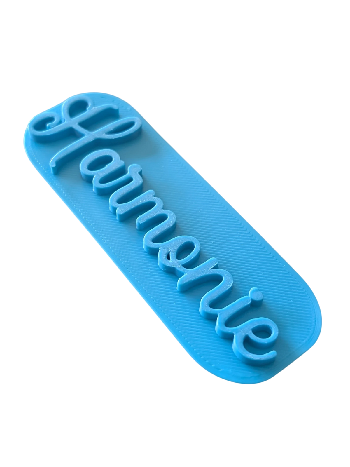 Perspektivische Detailansicht des blauen Stempels mit dem Schriftzug Harmonie und feinen Konturen für Töpferarbeiten.